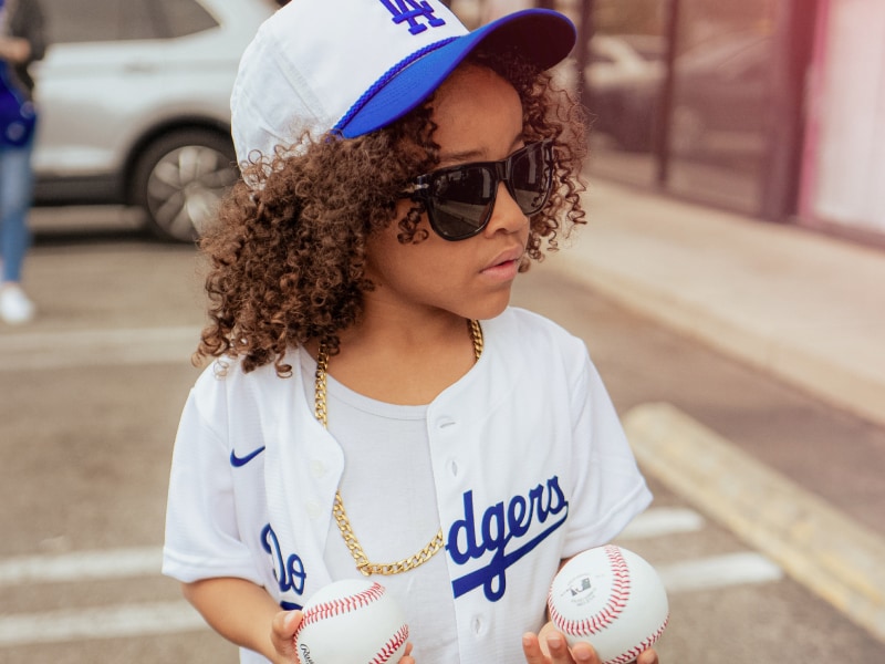 Child in a Los Angeles Dodgers jersey holding baseballs