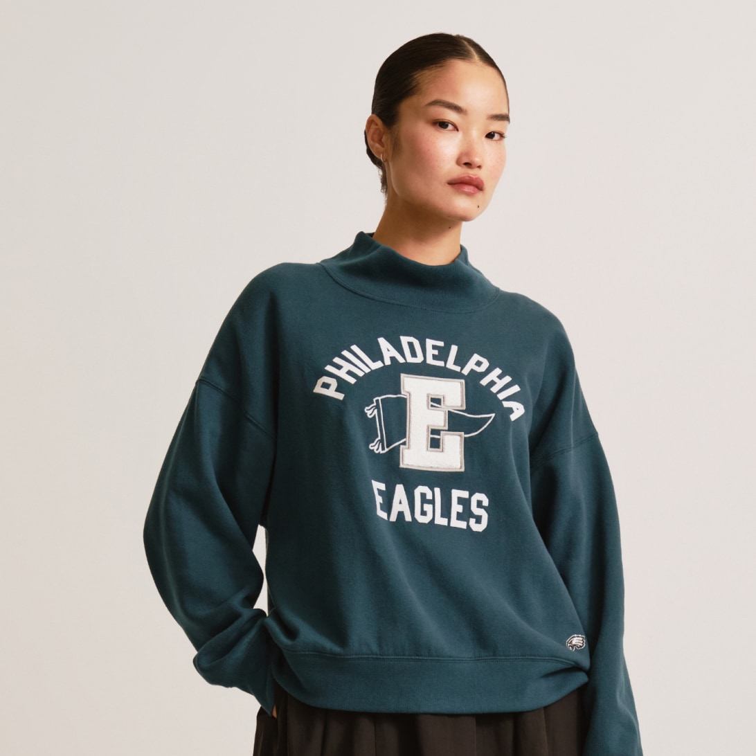 Woman in a teal Philadelphia Eagles mock-neck sweatshirt